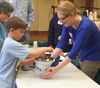 TSTI Young Family Engagement Coordinator, Alanna Carter helps 8-year-old Jack from West Orange make applesauce during a recent “Food for Thought” event