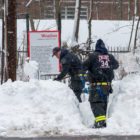 Firefighters shovel snow near sign with a poem